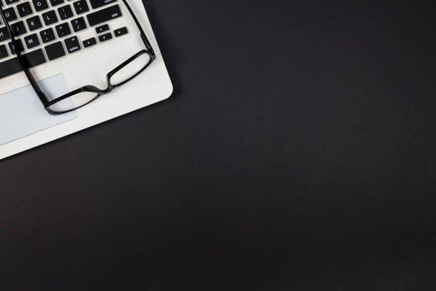 istock Top view of a keyboard with glasses on a black background with copy space. 2187338957