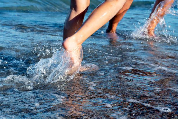 Female feet step on the sea wave