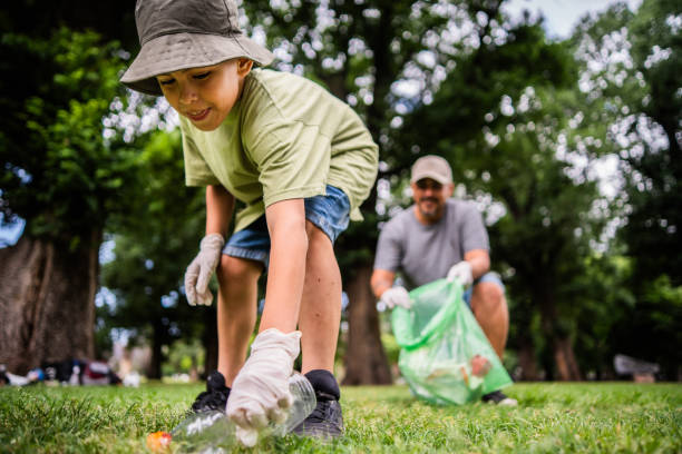 Child boy doing garbage collect with father on the public park