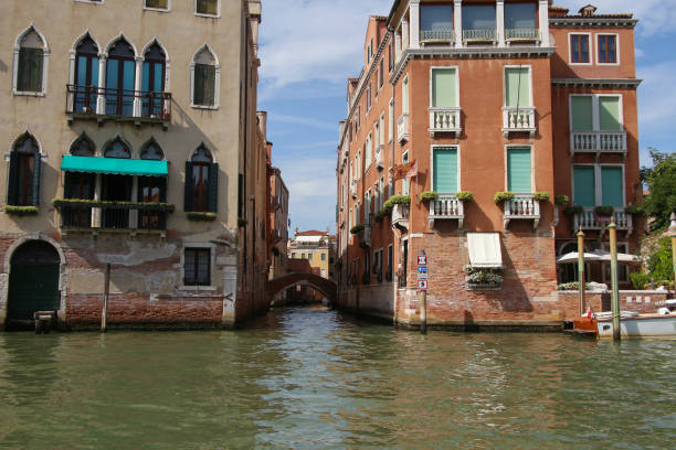 Side view of empty narrow water canal between residential brick buildings in a sunny summer day in Venice, Italy. Soft focus. Copy space. Old town Italian architecture. Vacation in Europe theme.