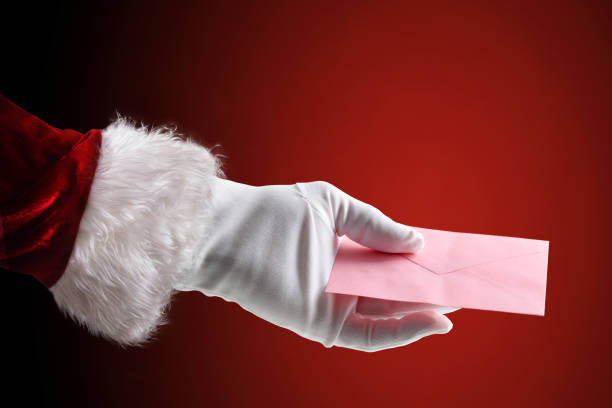 istock Santa Claus hand holding pink envelope on red isolated background 2187339529