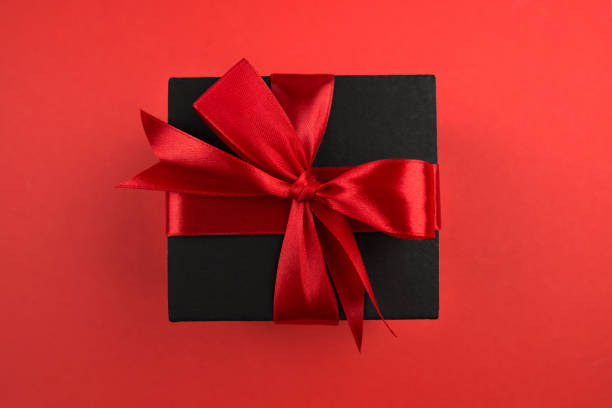 istock Top view photo of black gift box with red bow on isolated red background with empty space 2187339545