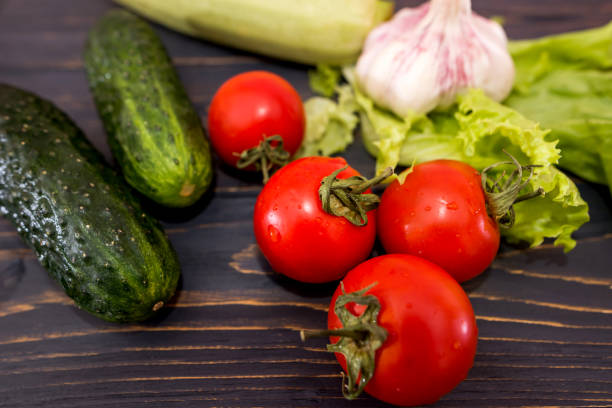 different vegetables on wooden boards. Tomatoes, cucumbers, lettuce and zucchini on a dark table. Close-up.