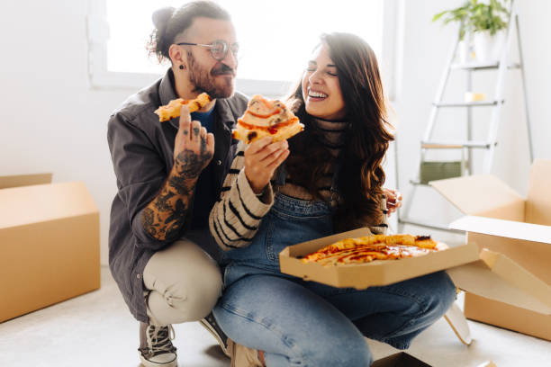 istock Young couple eating pizza in new home 2187344653