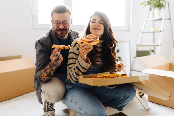 istock Young couple eating pizza in new home 2187345296