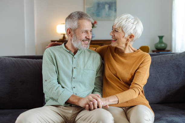 istock Cute married mature couple sitting on the sofa and embracing 2187345923