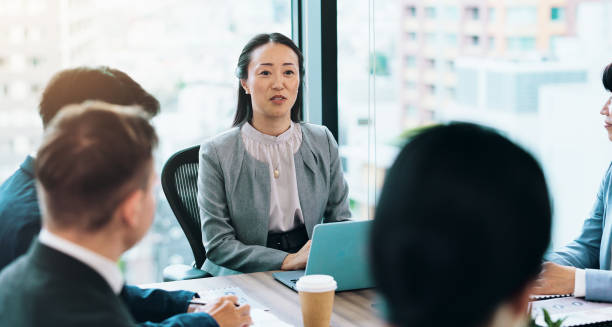 istock Woman, talking or business people meeting with group for feedback or discussion or teamwork. Corporate, investor or manager speaking to professional employees for project, advice or planning in Japan 2187347555