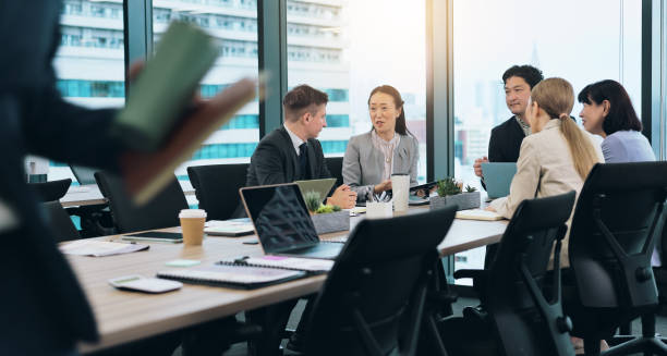 istock Asian, partnership or business people in meeting talking for feedback, discussion or teamwork. Corporate, staff or investor speaking to professional employees for project, group or planning in Japan 2187347568
