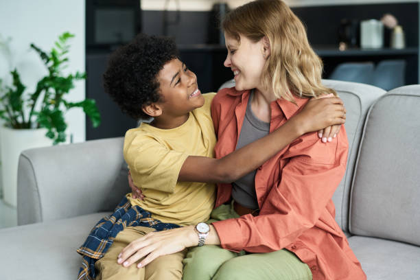 istock Smiling Child Embracing Caregiver on Cozy Sofa 2187351522