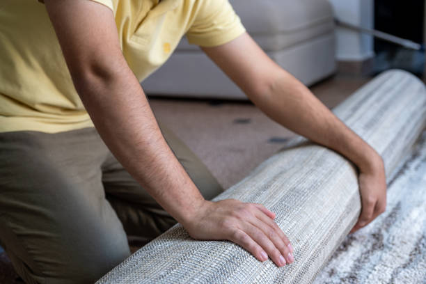 istock Smiling Man Rolling Out Carpet in Modern Living Room 2187352032