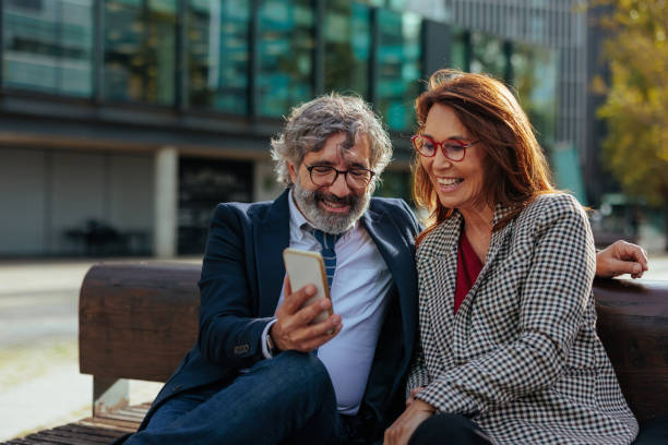 istock Smiling senior business people using smartphone outdoors 2187353027