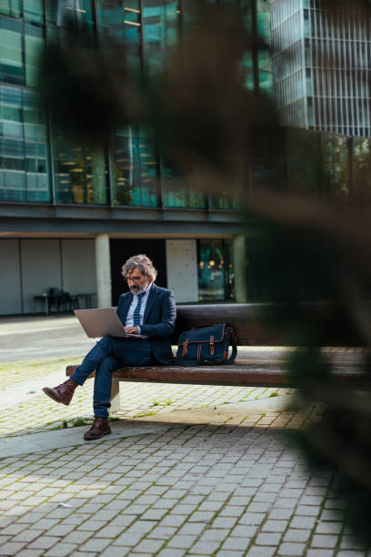 istock Businessman working on laptop outdoors in urban setting 2187353049