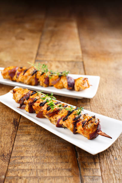 A beautifully styled plate featuring grilled chicken skewers served garnished with fresh thyme.