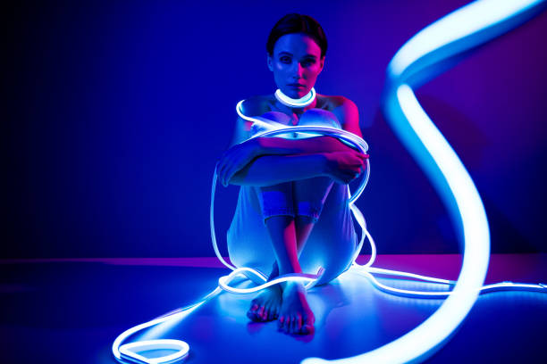istock Captivating young woman surrounded by glowing neon lights in a dark blue studio 2187353301
