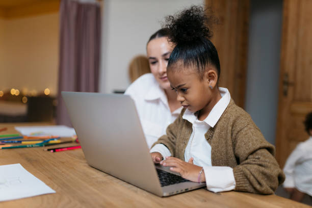 istock Mother teaching daughter using laptop at home 2187353331