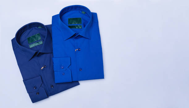 istock Two dark blue folded shirts on a colored background with copy space, top view 2187357314