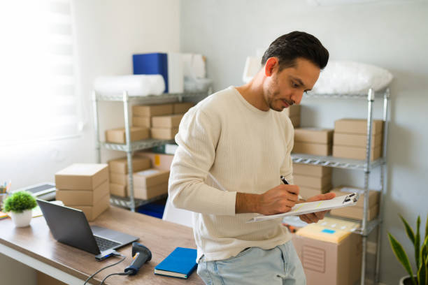 istock Good looking entrepreneur managing shipping and delivery details and making notes at his small business startup 2187360385
