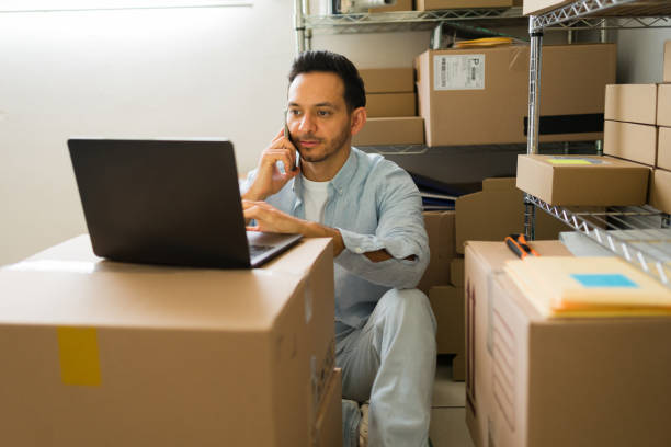 istock Latin entrepreneur managing his ecommerce from the storeroom, using laptop and smartphone to check orders 2187360735