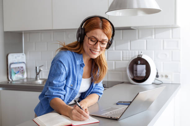 istock A cheerful woman writing notes while listening to online classes 2187361323