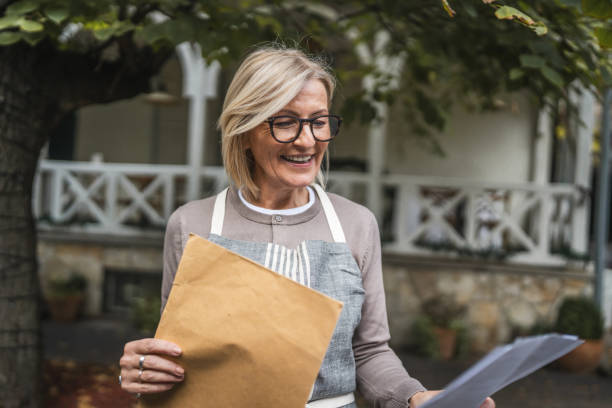 istock Mature woman waitress owner receive envelope mail in front restaurant 2187362159