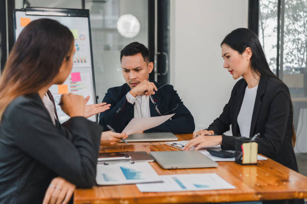 istock Business meeting with three professionals discussing project details, analyzing documents, and collaborating on strategies. atmosphere is focused and engaged 2187367047