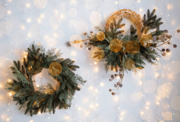 istock Holiday wreaths decorated with greenery and lights on white wall 2187368550