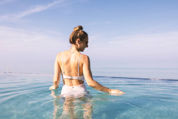 istock Woman in infinity pool with back to camera enjoying serene ocean view 2187372493