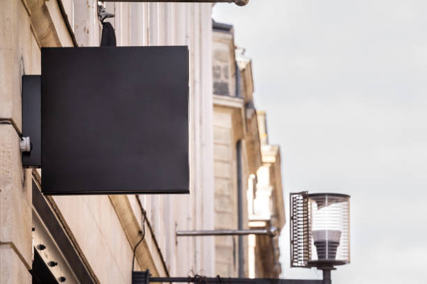 istock A blank black rectangular shop sign mounted on a building, ideal for branding or store identification in a commercial district. 2187372604
