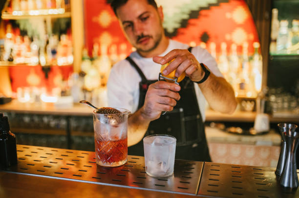 istock Male bartender preparing Negroni cocktail with an orange zest. 2187378212