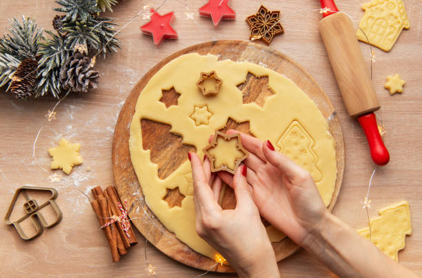 istock Woman making christmas cookies using star shaped cutters on wooden board 2187379892