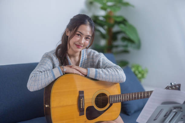 istock Woman Practicing Acoustic Guitar at Home 2187381116