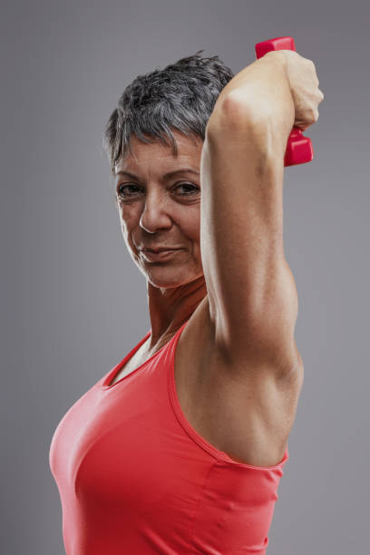 istock Determined senior woman lifting weights and smiling at camera 2187382092