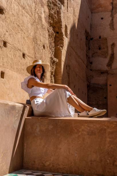 istock Woman in white sitting on ancient stone in sunlight. 2187382599