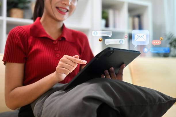 istock Smiling young woman using digital tablet with with social media notifications bubbles surrounding 2187386753