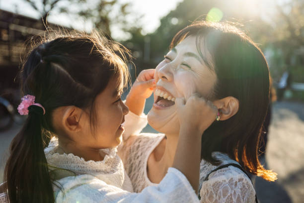 istock Daughter pulling cheeks of her laughing mother in tokyo, japan 2187395703