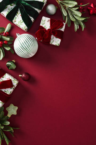 istock Christmas vertical background with elegant ornaments and gift boxes on rich red table. 2187395845