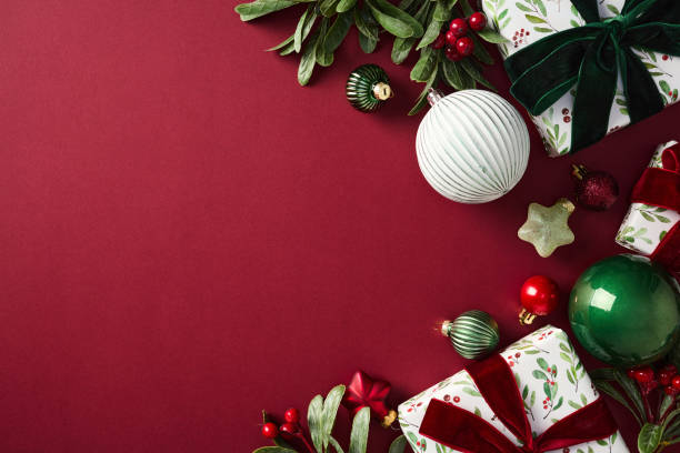 istock Christmas decorations on red background: green and red ornaments, gift box, branches with berries. Perfect for seasonal greetings, holiday marketing, and vibrant festive content 2187395887