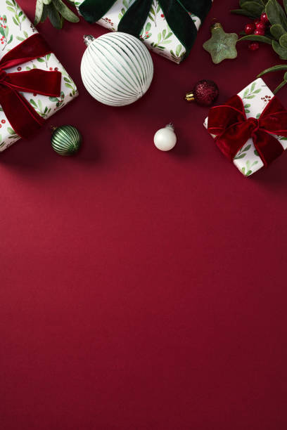 istock Chic Christmas vertical background with gift boxes, balls, Xmas ornaments, branches with berries on red table 2187395995