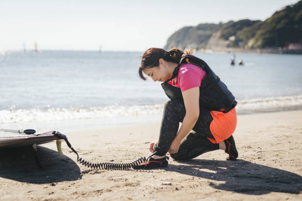 Asian woman in her 40'ssetting leash cord  on her leg before doing SUP.