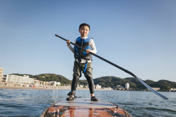 istock Asian boy playing standup paddle boarding 2187397415