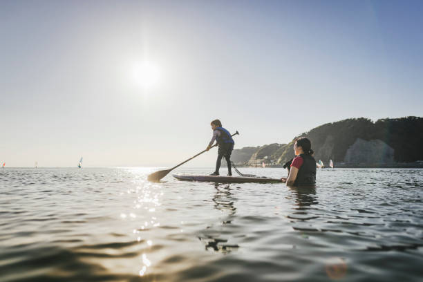 istock Mother and daughter playing stand up paddle boarding. 2187397417
