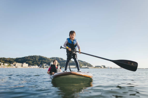 Mother and daughter playing stand up paddle boarding.