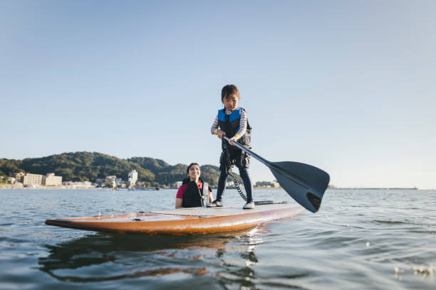 istock Mother and daughter playing stand up paddle boarding. 2187397419