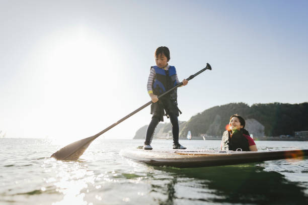 istock Mother and daughter playing stand up paddle boarding. 2187397423