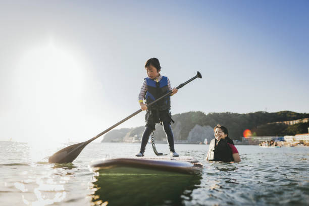istock Mother and daughter playing stand up paddle boarding. 2187397424