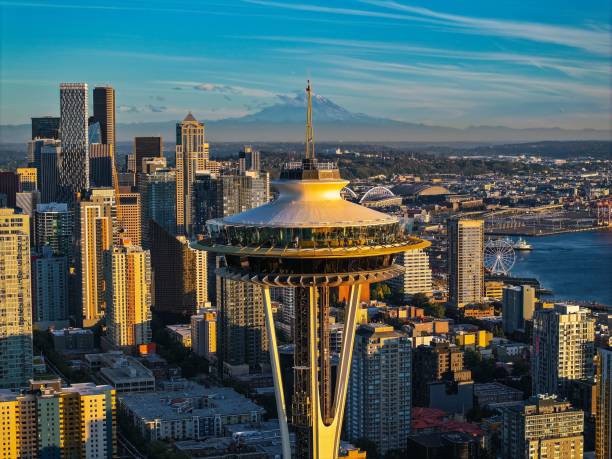 Seattle, United States – September 25, 2024: A breathtaking view featuring the iconic Golden Space Needle standing tall against the vibrant hues of a sunset-lit sky with Mt Rainier
