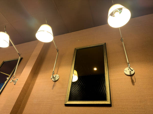 istock A mirror is hanging on a wall with two lamps above it 2187400307