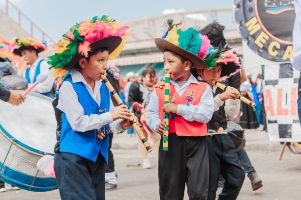 Moquegua, Peru - November 25, 2024 - Parade of traditional dances in southern Peru on a very hot day. Children in the foreground in traditional clothes playing their wind instruments.