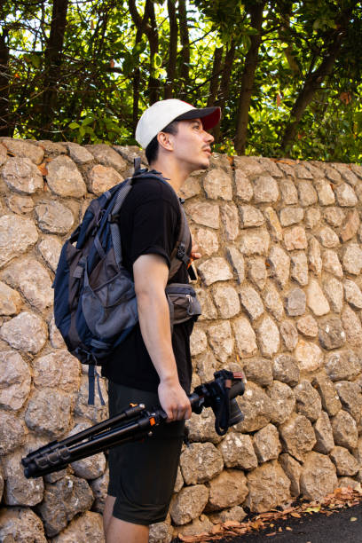 istock Adventurer holding tripod with camera in hand looking around 2187401604
