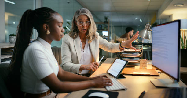 istock Night, people and computer in office for advice, project planning or feedback at desk. Woman writer, mentor and tech screen in agency for article report, proofreading or editing research for deadline 2187408435